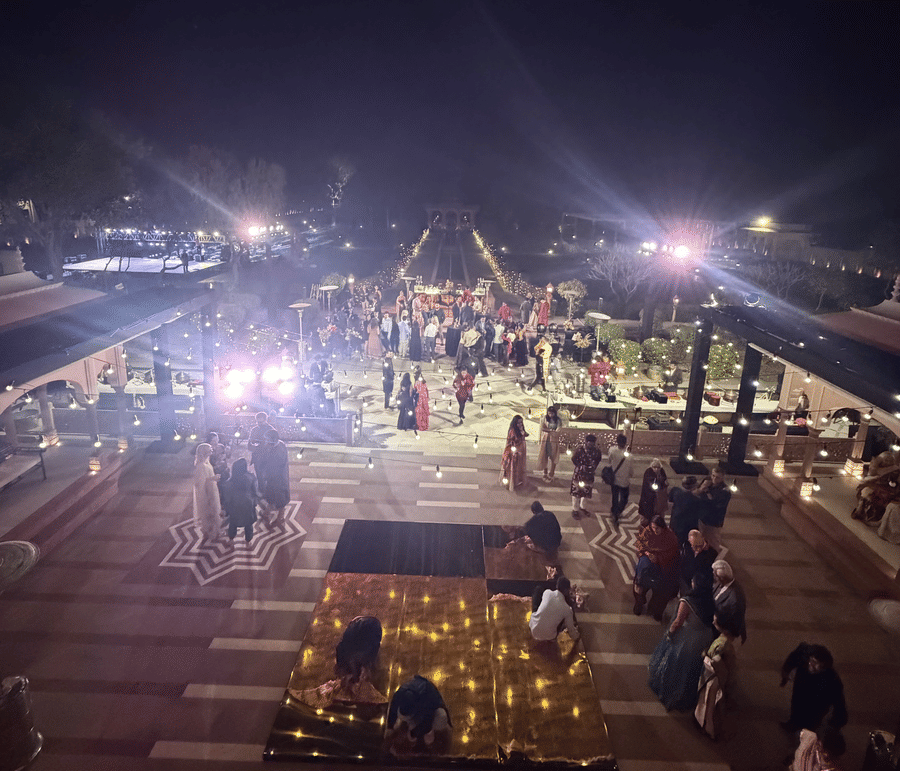 An aerial view of a beautifully illuminated courtyard at Umaid Palace during a night wedding reception with glowing lights and guests gathered.