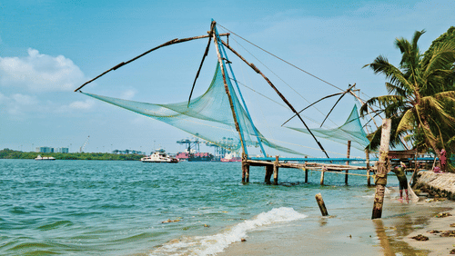 A traditional Chinese fishing net (Cheena Vala) standing over the water on a beach in Fort Kochi.