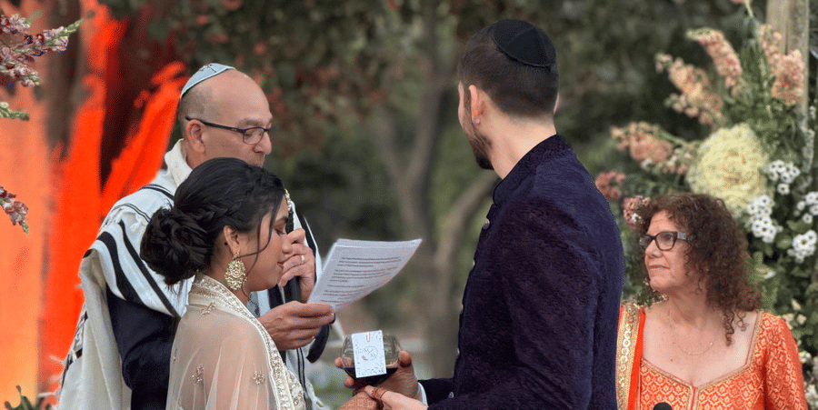 A bride and groom exchange vows during an outdoor wedding ceremony beneath a canopy at Umaid Palace.