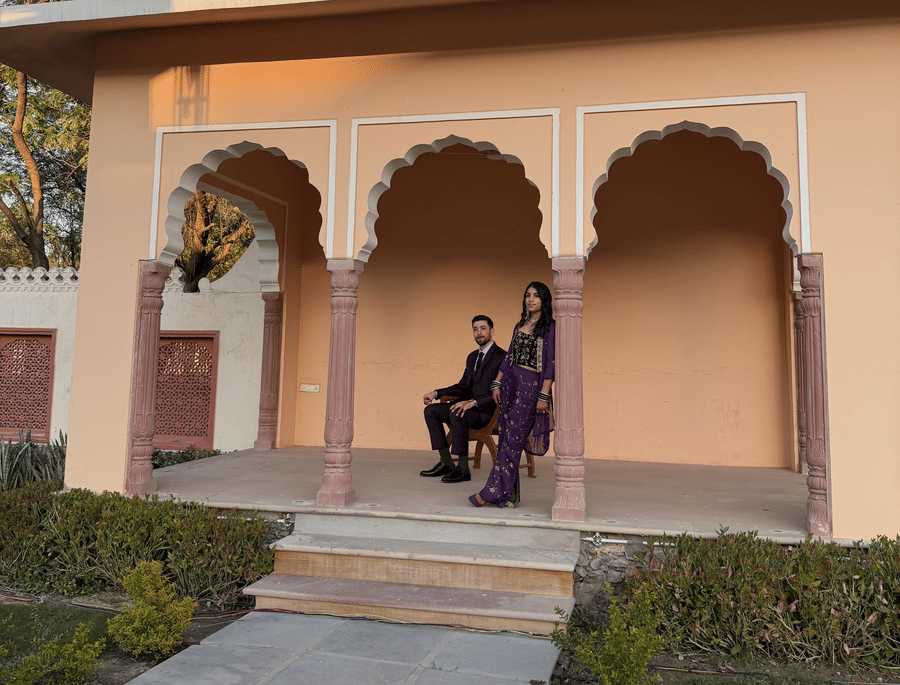 A traditional arched stone pavilion with people seated inside overlooking a garden path at Umaid Palace.