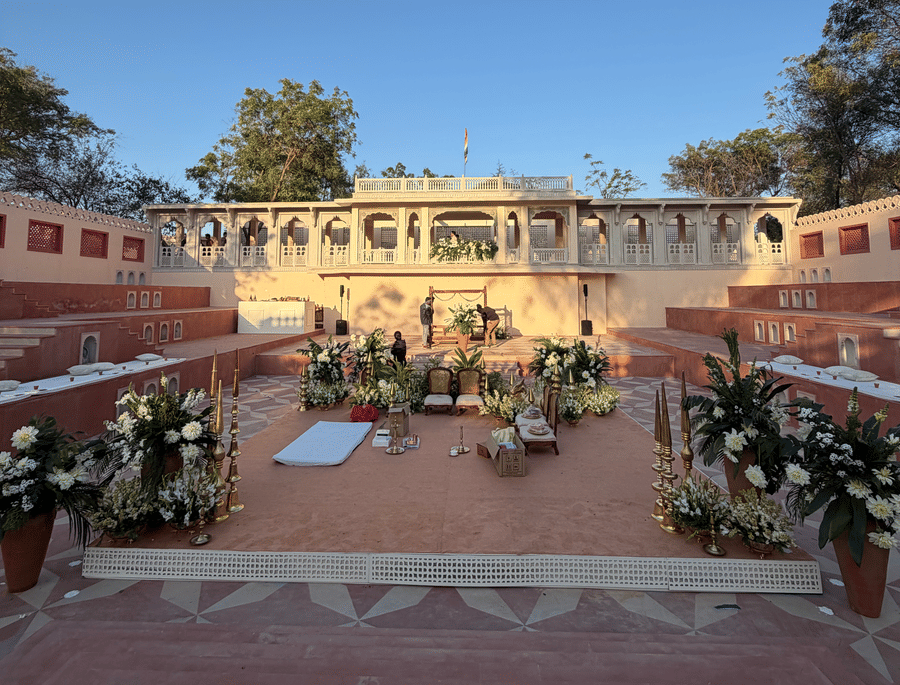 A high-angle view of a traditional stone stepped courtyard decorated with floral arrangements for a ceremony at Umaid Palace under a clear blue sky.