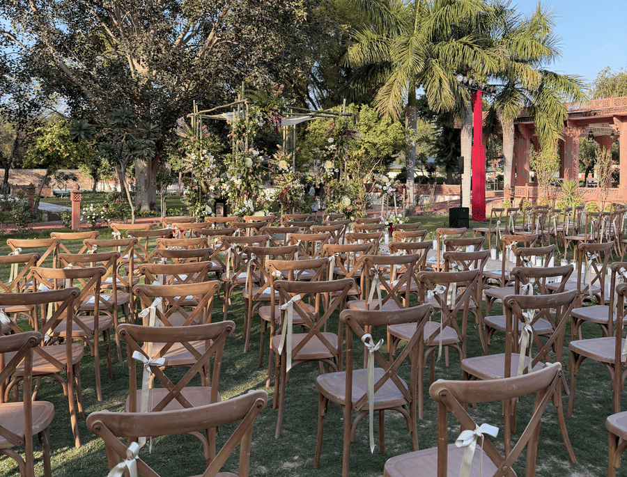 Rows of cross-back wooden chairs set up on the grass for an outdoor wedding ceremony at Umaid Palace.