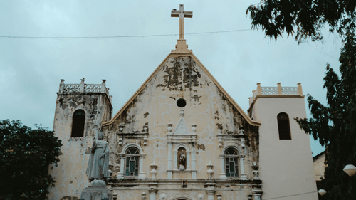Historic white church building with people walking towards the entrance.