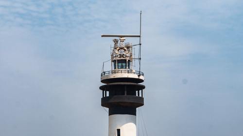 Black and white lighthouse standing tall against a clear blue sky.
