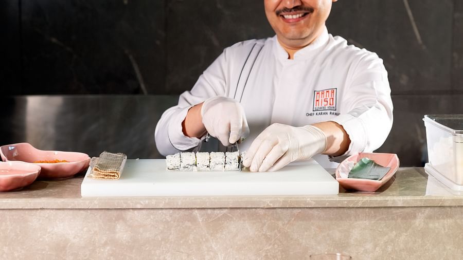 a chef smiling as he slices sushi a Mama Miso restaurant in Manesar