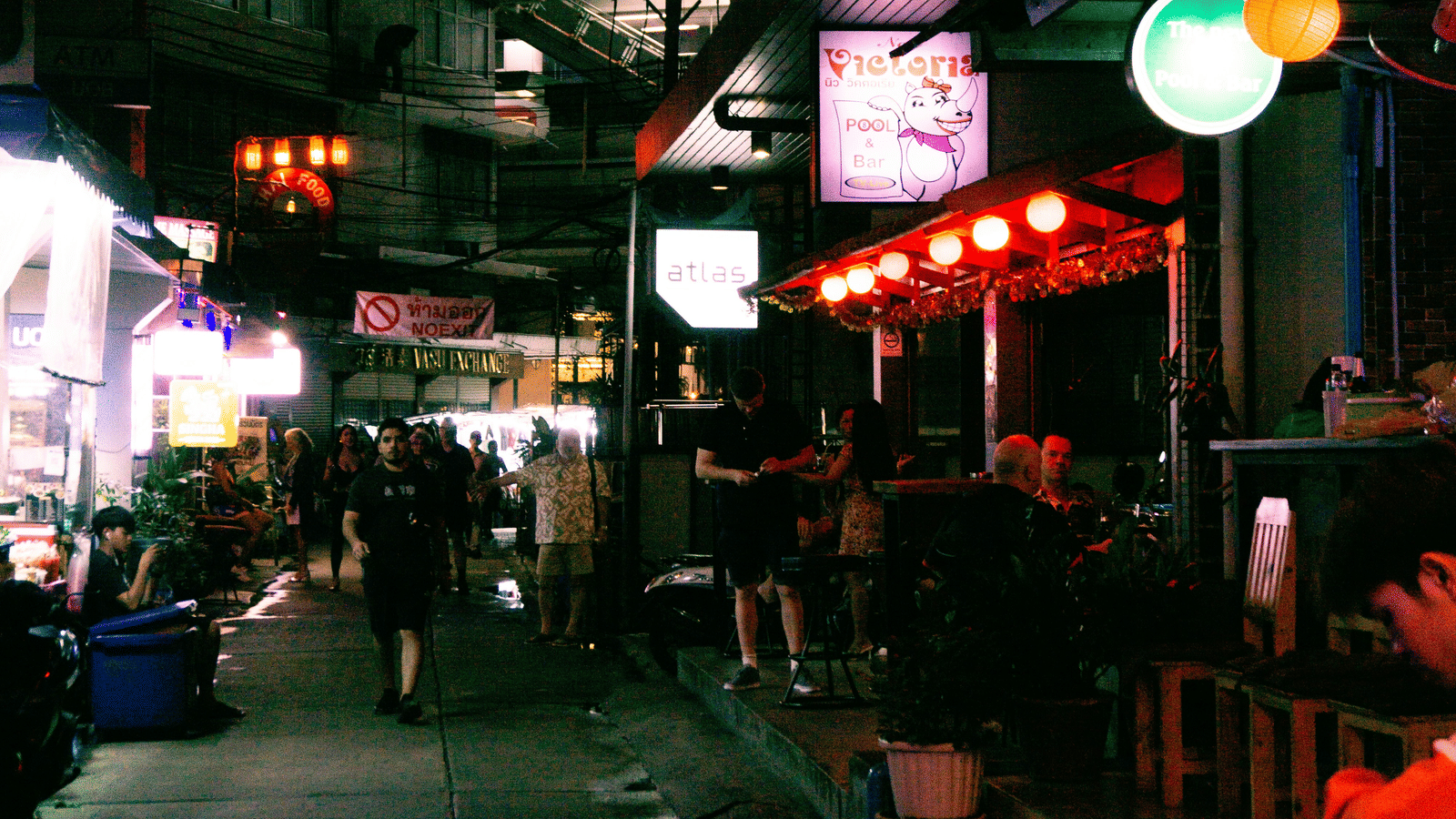 A view of the street near Nana Plaza with people walking during nighttime. 