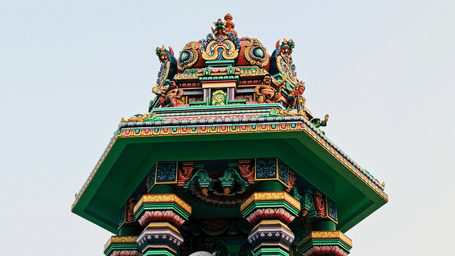 Colourful temple chariot tower rising against a clear sky, showcasing traditional South Indian architecture and festive craftsmanship during a cultural celebration.