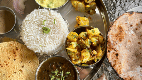 A full plate with several dishes plated on it along with butter jowar roti.