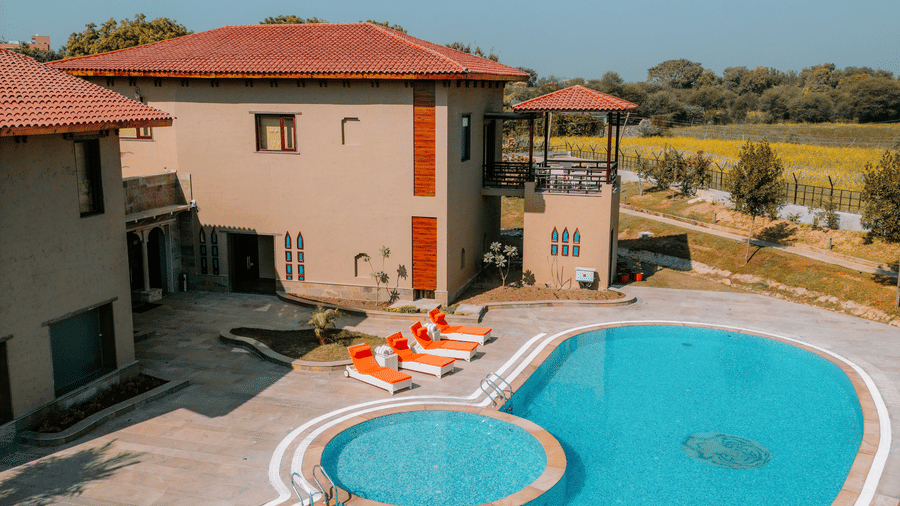 An inviting swimming pool with a unique shape beside a resort building at Aamaghati Wildlife Resort.