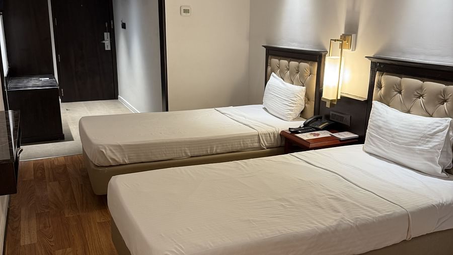 A spacious room with twin beds and a table with a light lamp in between | Cenneys Gateway