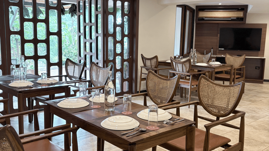 Brightly-lit restaurant interior featuring contemporary wooden furniture - Lords Riverside Resort, Muduba - Shivamogga