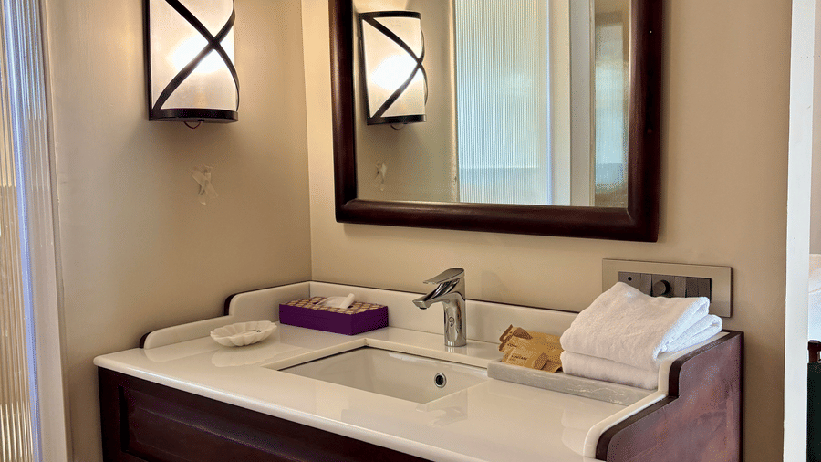Bathroom of Vana Suite at Surpura Bagh featuring a sink and faucet, mirror attached to the wall, towels, and other toiletries.