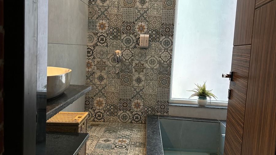 Modern bathroom with patterned tiles and enclosed shower area at Tisya Farms, Gurgaon.