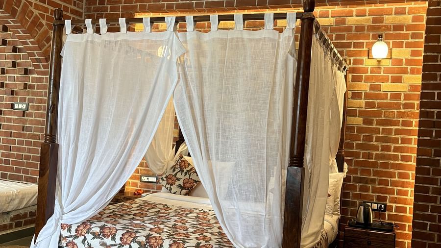 Bedroom with a four-poster canopy bed, brick wall accents, and warm lighting at Tisya Farms, Gurgaon.