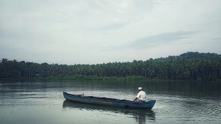 A man row boats on a river, surrounded by lush forests and calm waters, enjoying a peaceful and scenic natural setting.