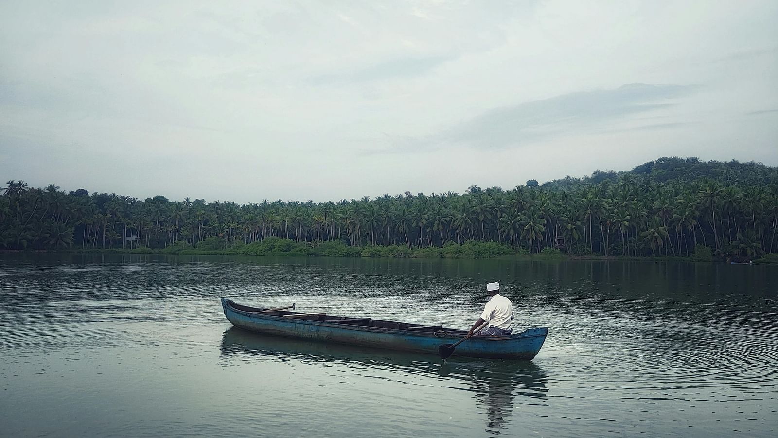 A man row boats on a river, surrounded by lush forests and calm waters, enjoying a peaceful and scenic natural setting.