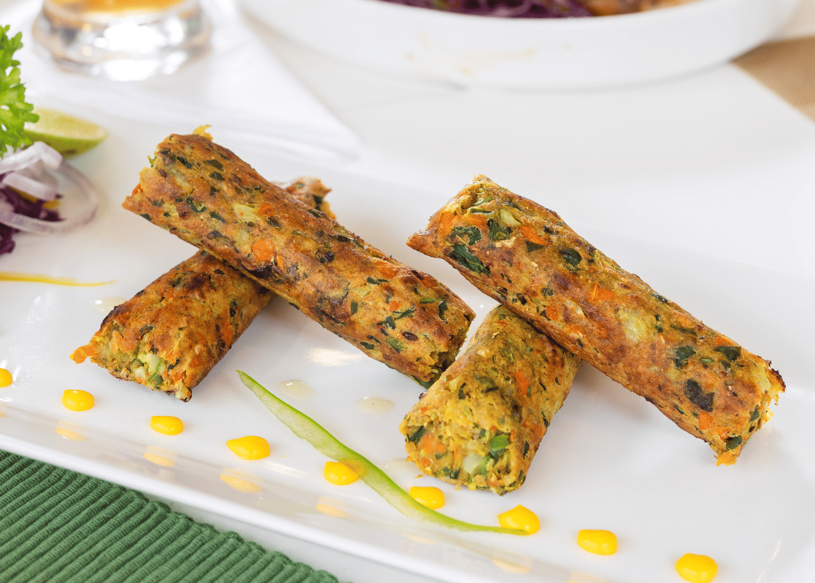 A white rectangular dish holds several fried spring rolls drizzled with a sauce - Megha Resort & Villas, Dehradun