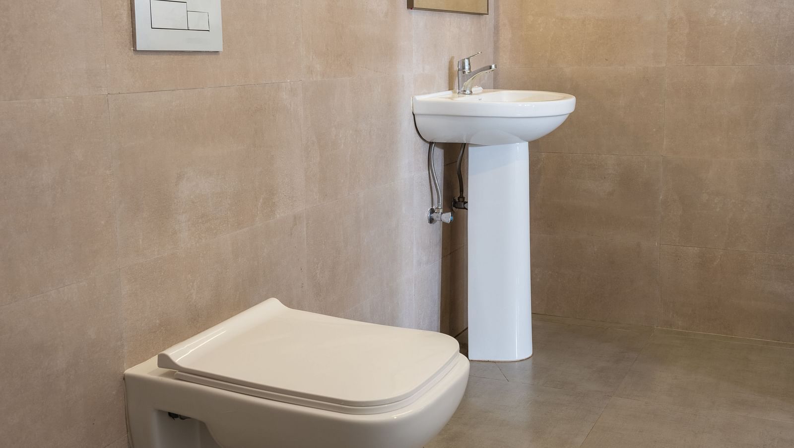 Modern bathroom with a wall-mounted toilet, sink, and a large mirror.