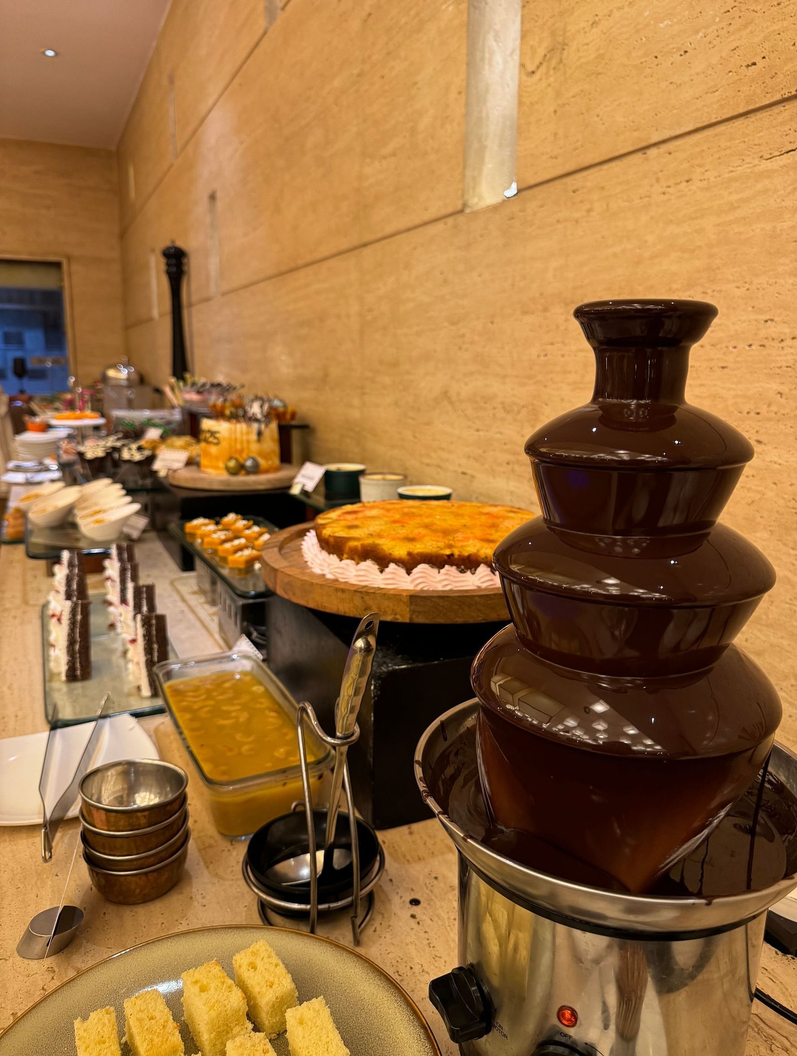 A chocolate fountain with various dipping items arranged on a buffet table at Cenneys Gateway.