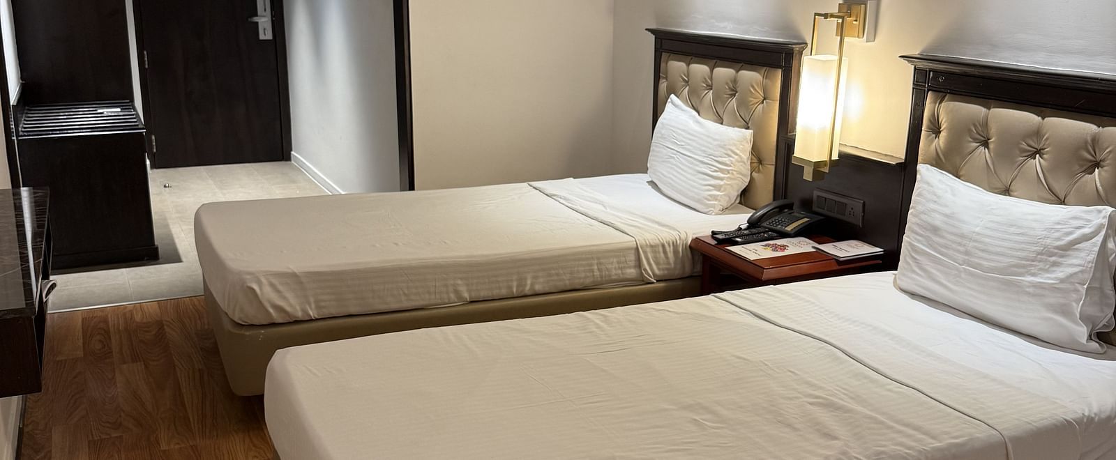A spacious room with twin beds and a table with a light lamp in between | Cenneys Gateway