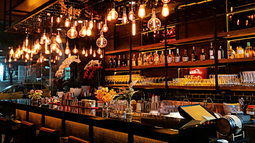 Upscale cocktail bar with illuminated shelves, premium spirits, elegant lighting, and a sophisticated nightlife atmosphere