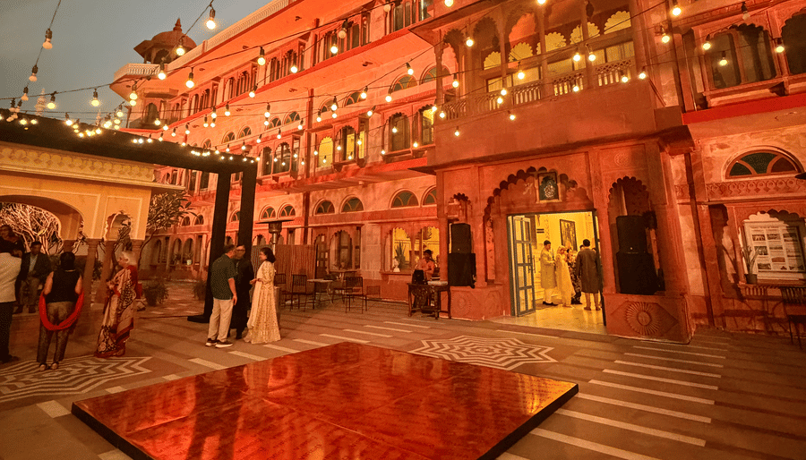 An outdoor dance floor illuminated at night with overhead string lights in front of a grand, brightly lit heritage building at Umaid Palace.