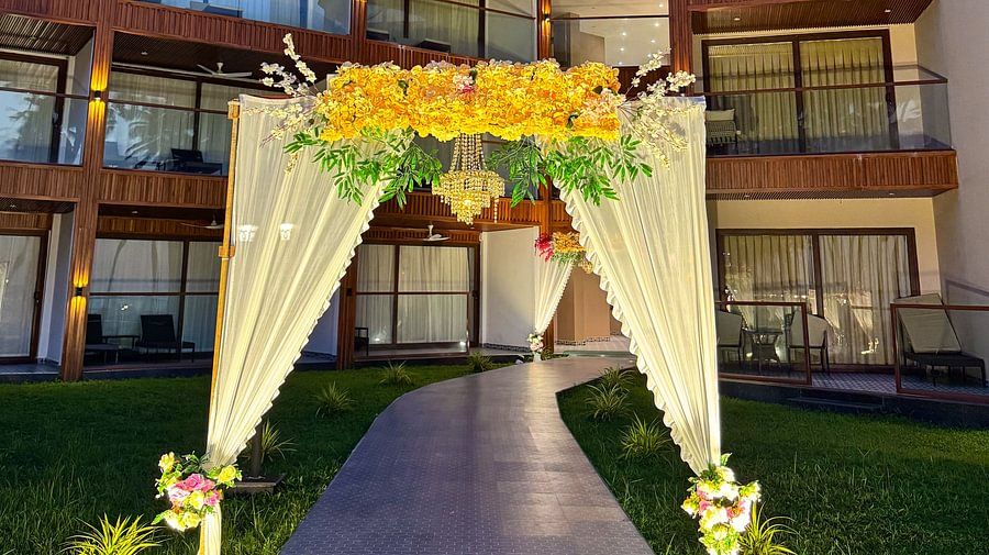 An outdoor pathway with a floral arch leading to the hotel building at Silver Sand Sea Princess Beach Resort, Port Blair, at dusk.
