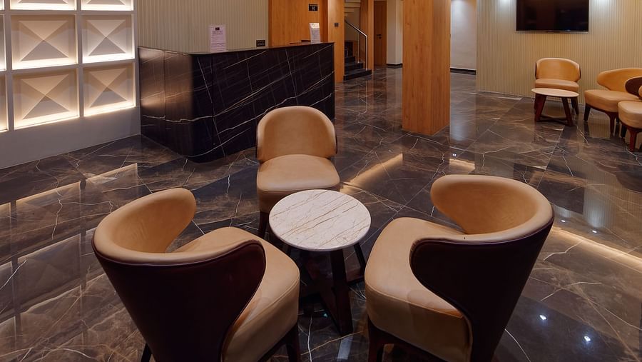 Lobby with seating chairs and light hanging from the ceiling Side view of twin beds with a television in font and ceiling on the wall at Ankit Hotel, Jabalpur