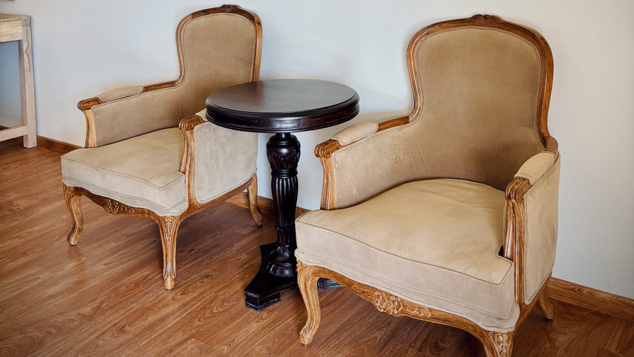 Seating area at Vana Junior Suite featuring two sofa chairs and a centre table. Above the seating area there are two lit lamps.