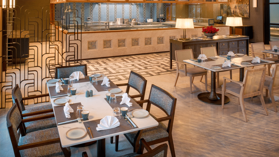 Side view of Chin Chin restaurant at The Residency Signature Madurai with dining tables, copper wall panels, and warm ambient lighting.