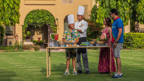 2 guests setting up for an outdoor meal or cooking activity on the lawn at Heritage Village Resort & Spa, Manesar.