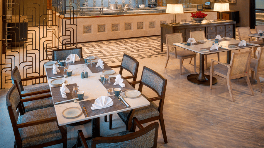 Side view of Chin Chin restaurant at The Residency Signature Madurai with dining tables, copper wall panels, and warm ambient lighting.
