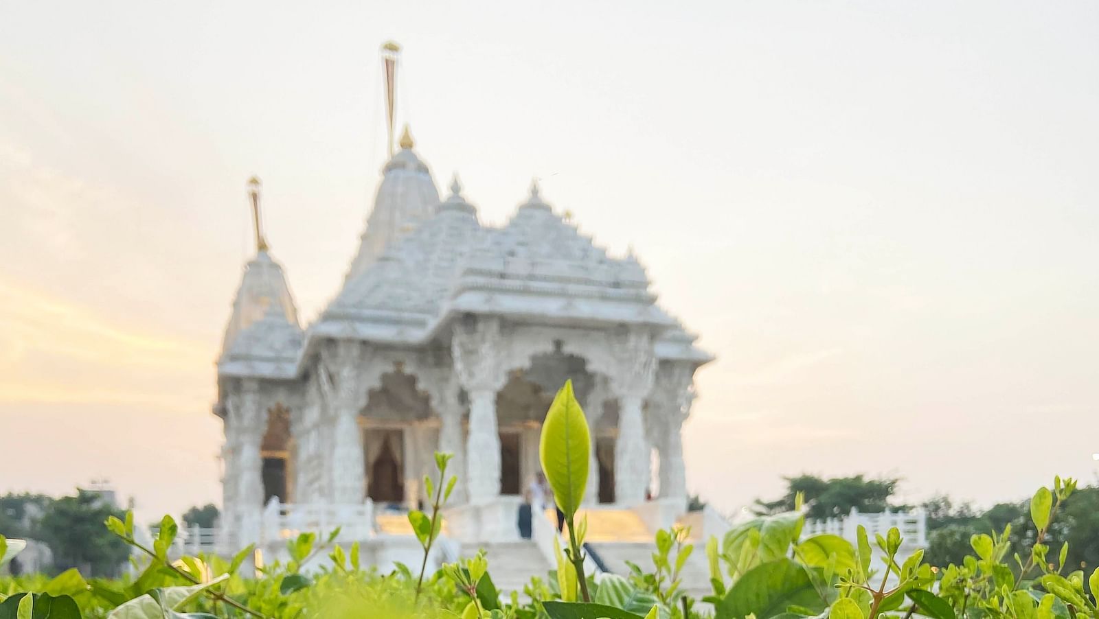 A far out view of a jain temple with the sun shining behind it