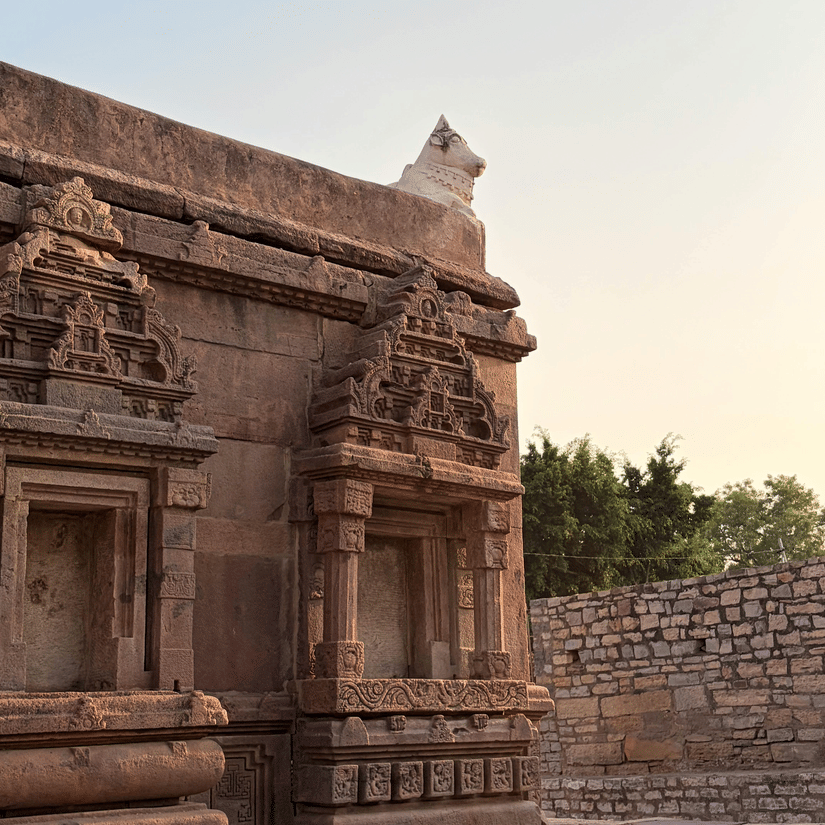 Intricately carved stone architecture of a temple glowing under soft evening light with detailed pillars and sculptures in view.