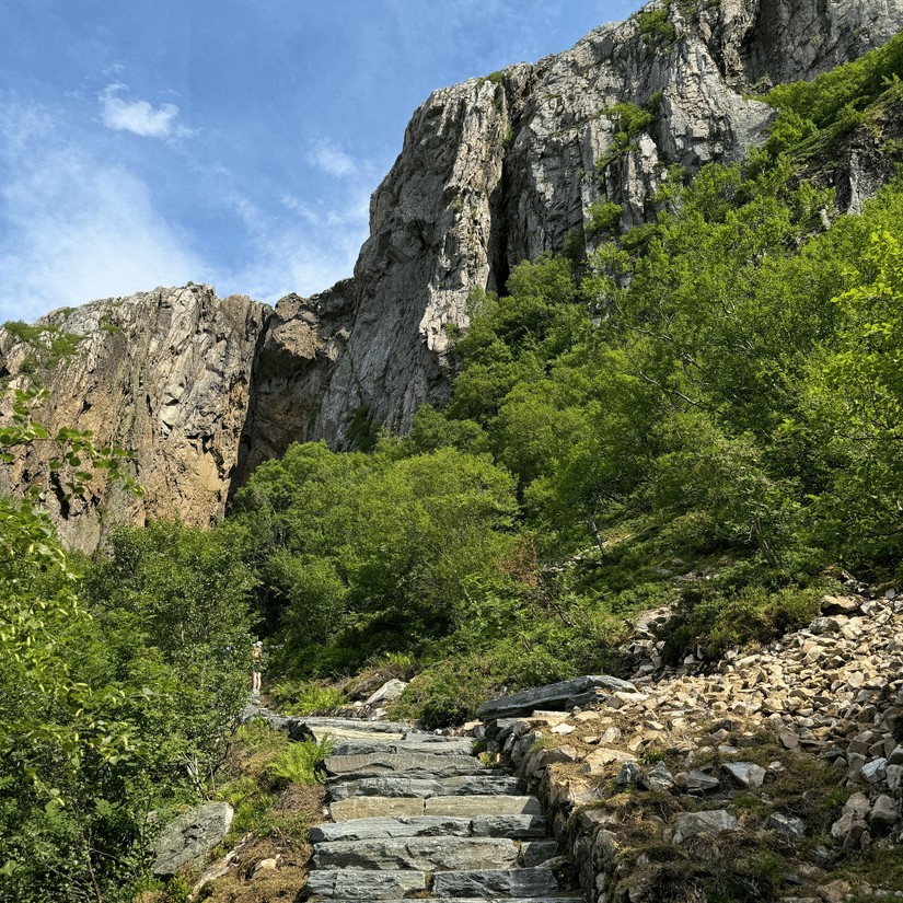 A view of a makeshift steps made from rocks, with a mountain and blue sky in the background. Pandavleni Caves entry fee is extremely nominal at Rs. 2.