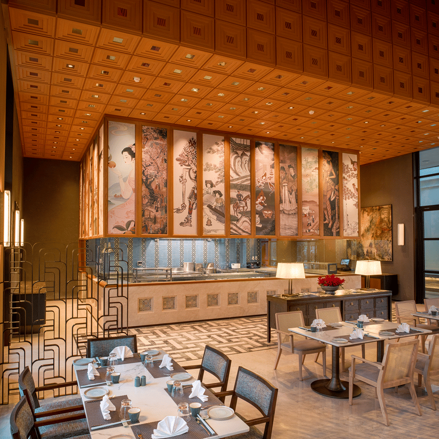 Side view of Chin Chin restaurant at The Residency Signature Madurai with dining tables, copper wall panels, and warm ambient lighting.