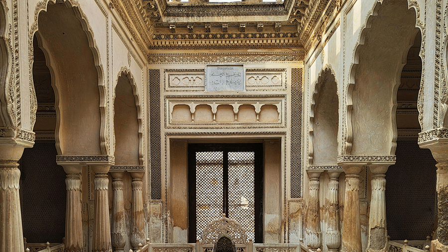 Grand symmetric architecture of an ancient palace courtyard featuring stone arches and a central water structure.