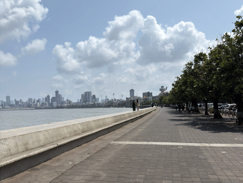 A scenic view of Marine Drive in Mumbai with clear skies and city skyline in the background.