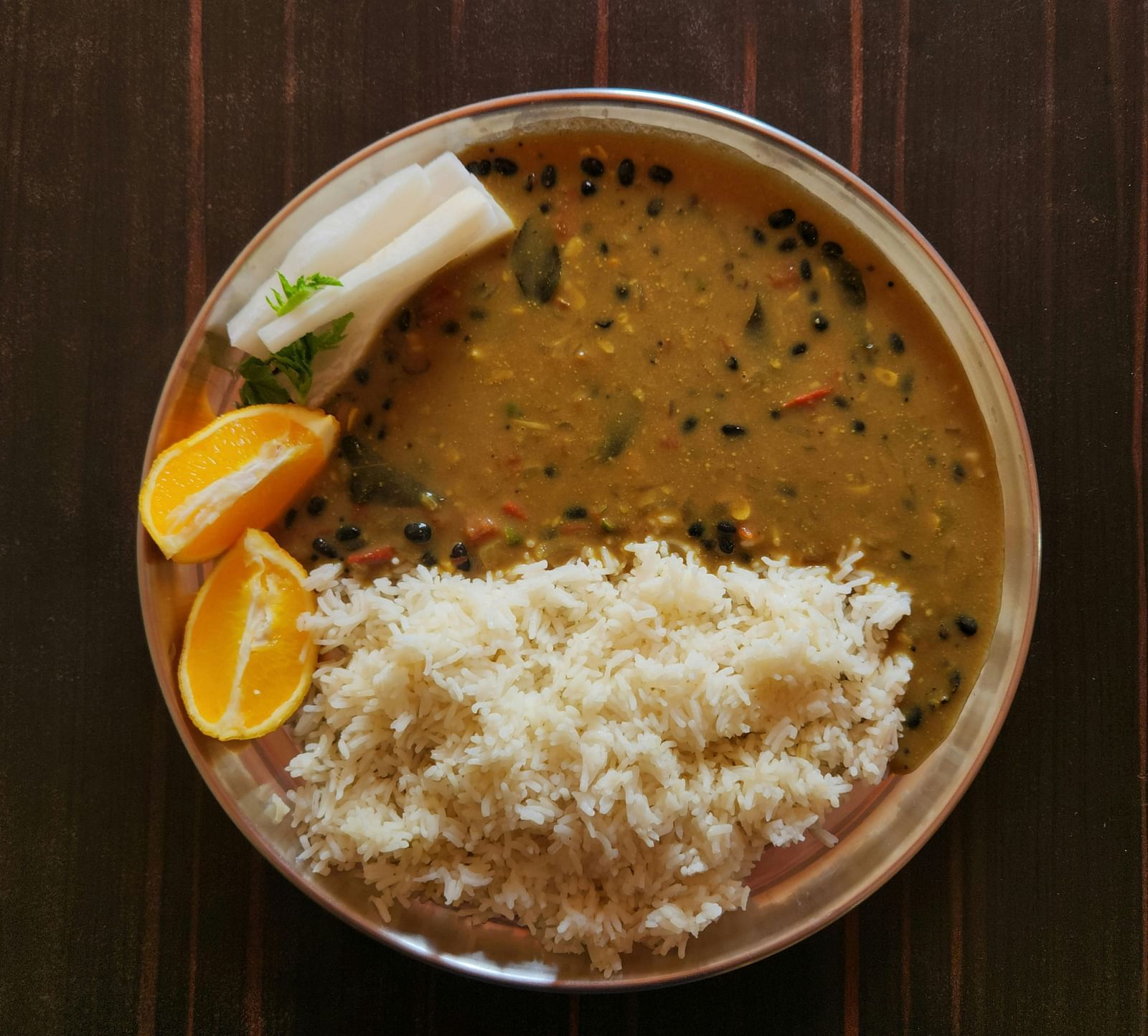 An image of a rice bowel with lentil soup, lime, and other vegetables