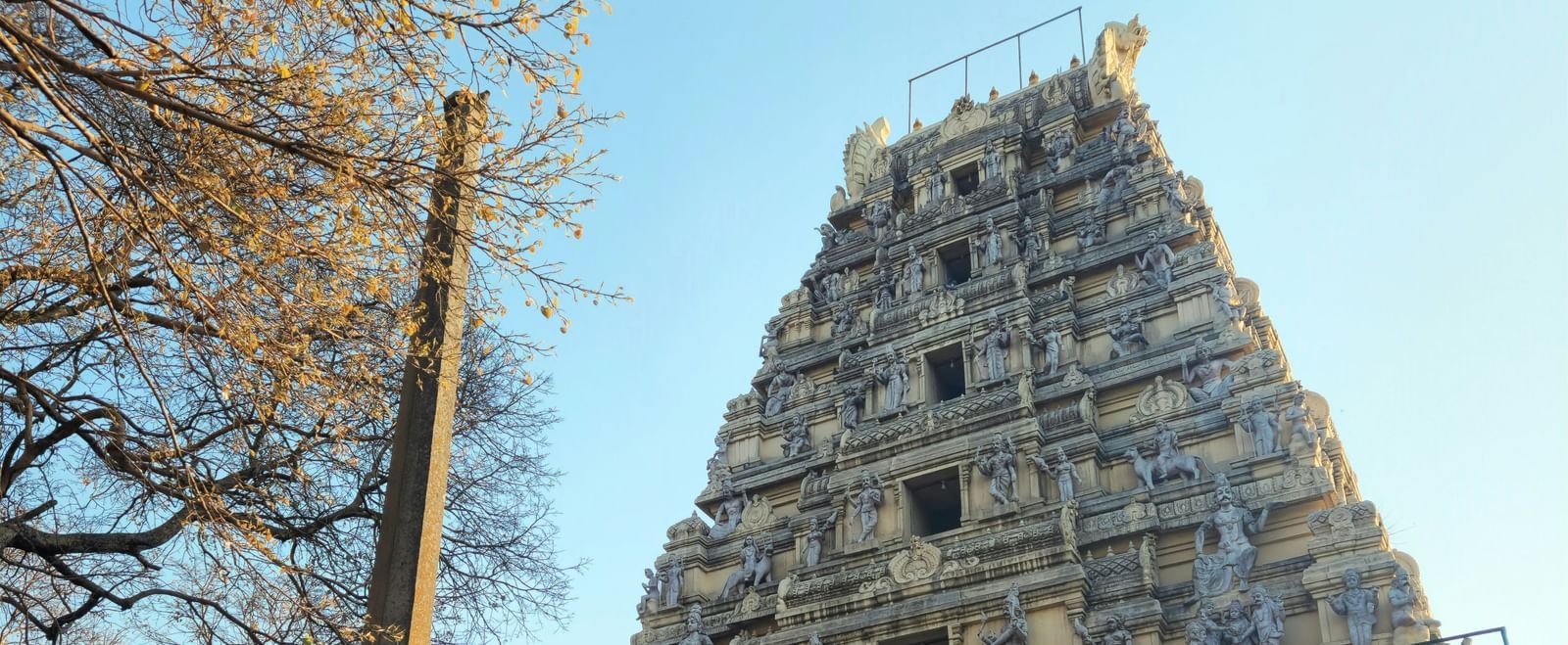 A front view of the temple with detailed architecture surrounded by trees under a clear sky.