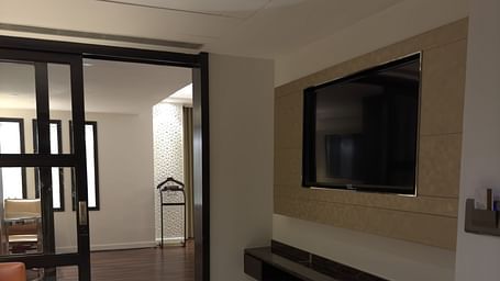 A room with a bed, a seating area, and a wall-mounted television at Cenneys Gateway.