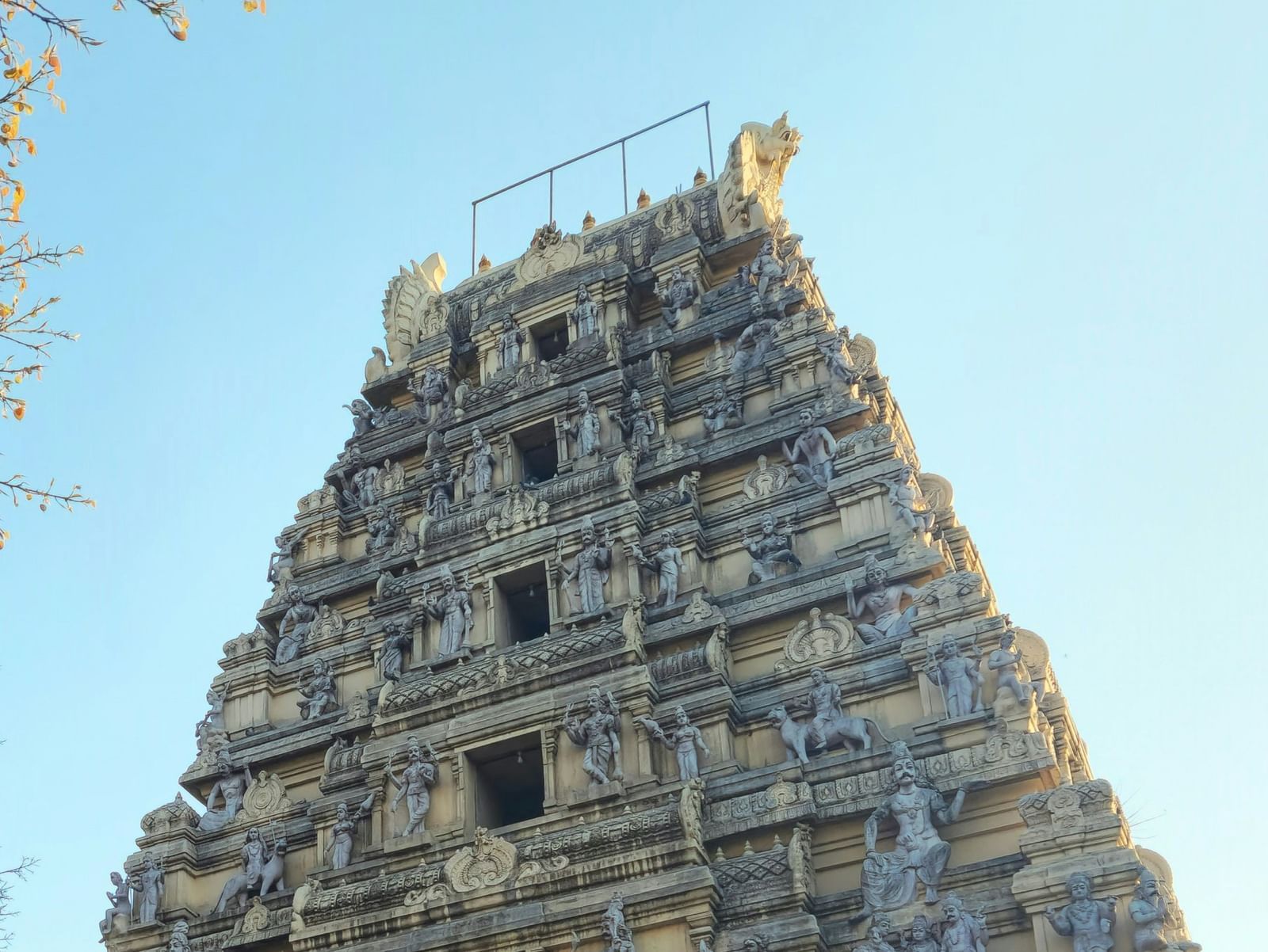 A white temple with a decorated gopuram and a colourful statue at the front entrance.