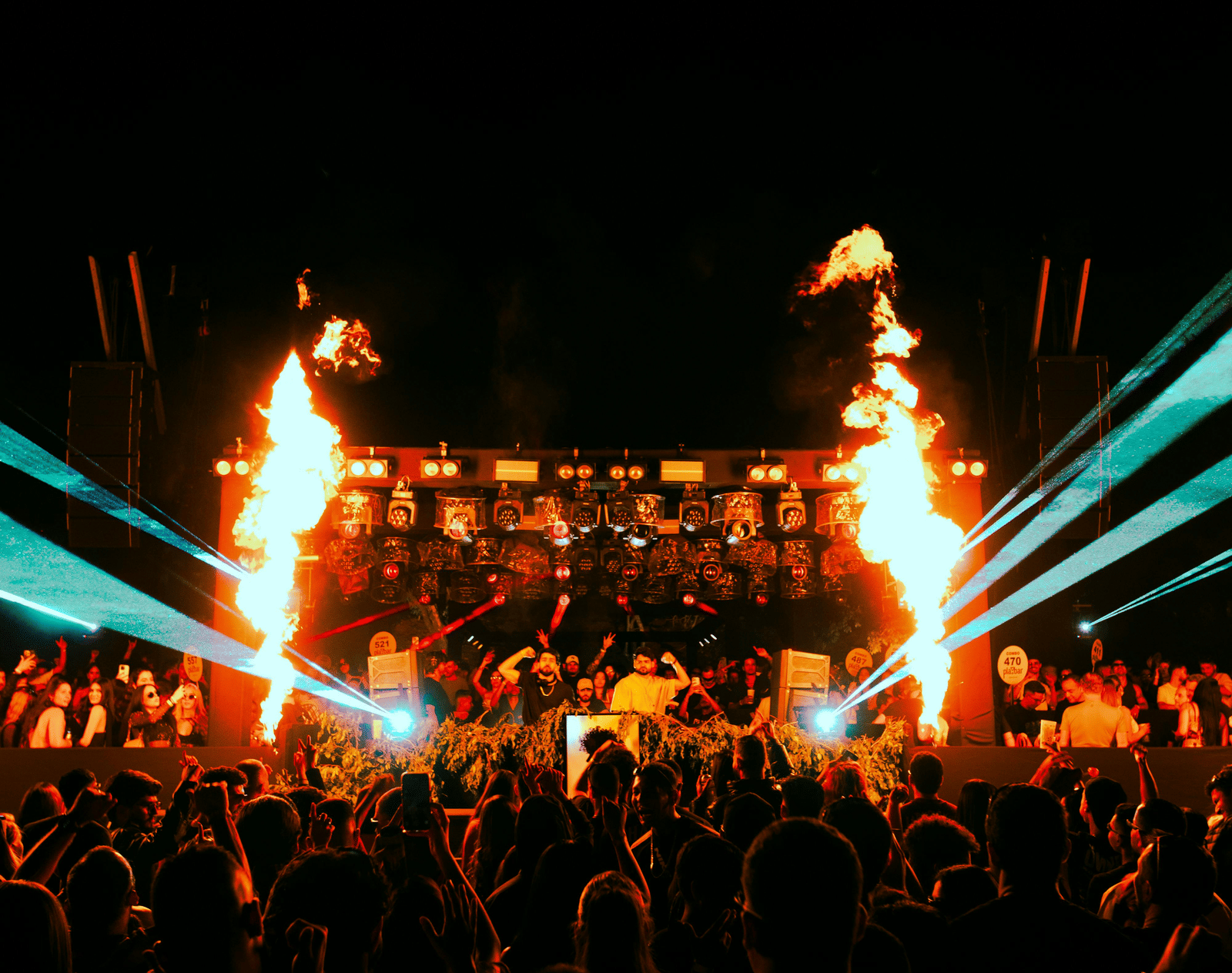 A lively night concert with a cheering crowd illuminated by bright stage lights.