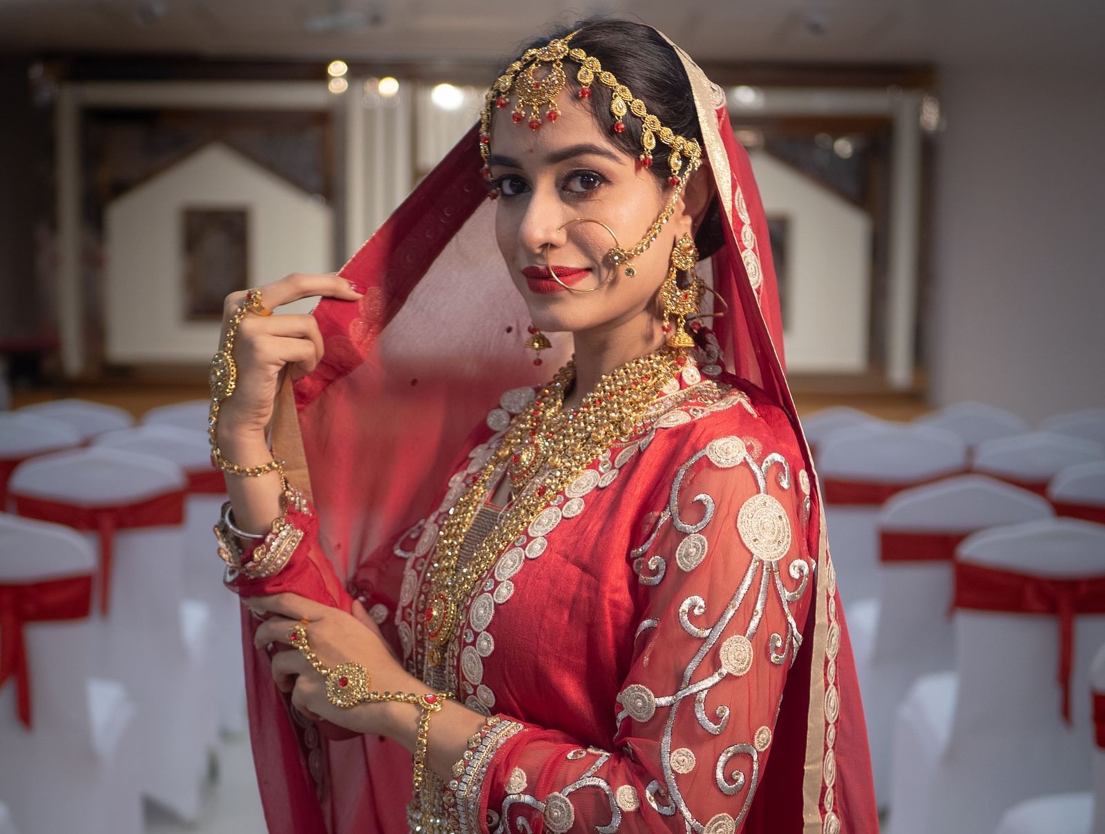 Bride in red attire posing in a hallway decorated for a wedding at Mansha Regency, Port Blair.