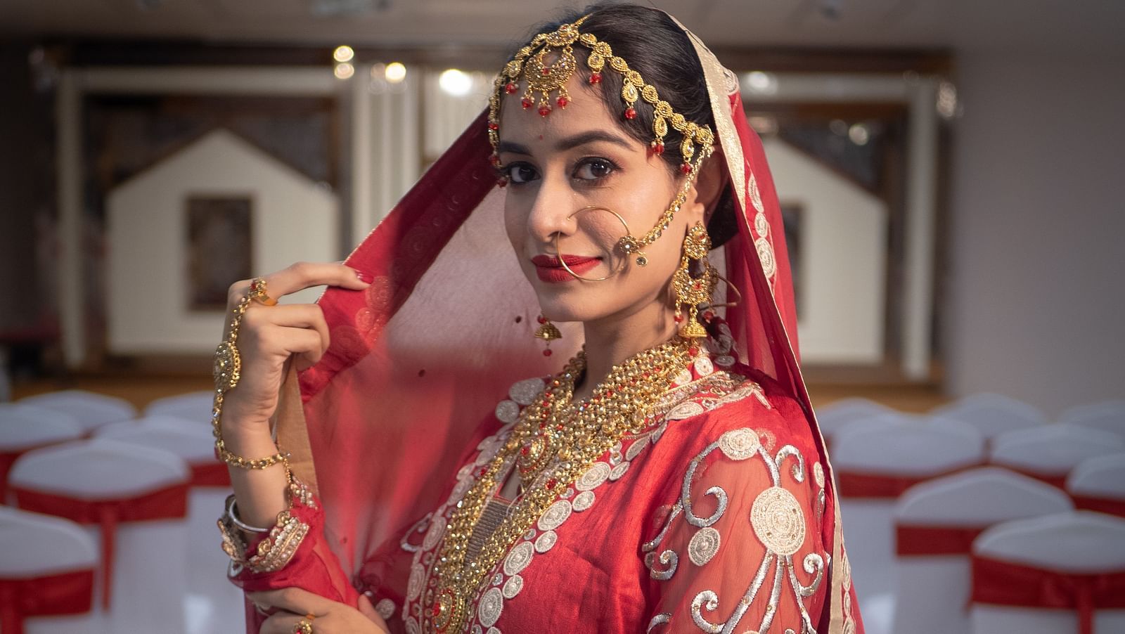 Bride in red attire posing in a hallway decorated for a wedding at Mansha Regency, Port Blair.