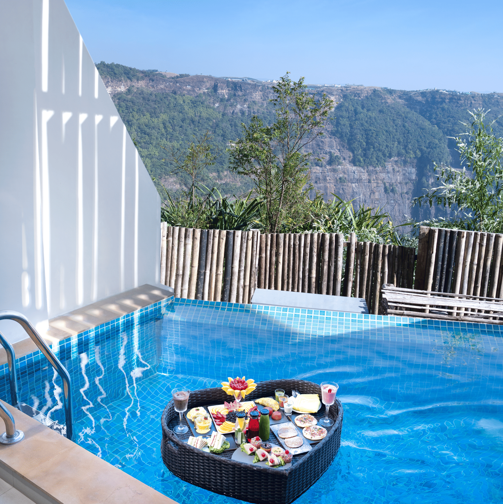 Private plunge pool at Polo Resort Cherrapunji with a floating heart-shaped breakfast tray, bamboo screen and valley views beyond.