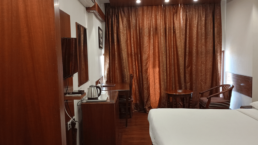 Bedroom at Hotel Gold, Panipat with a bed, curtains, and a work desk placed along the wall.