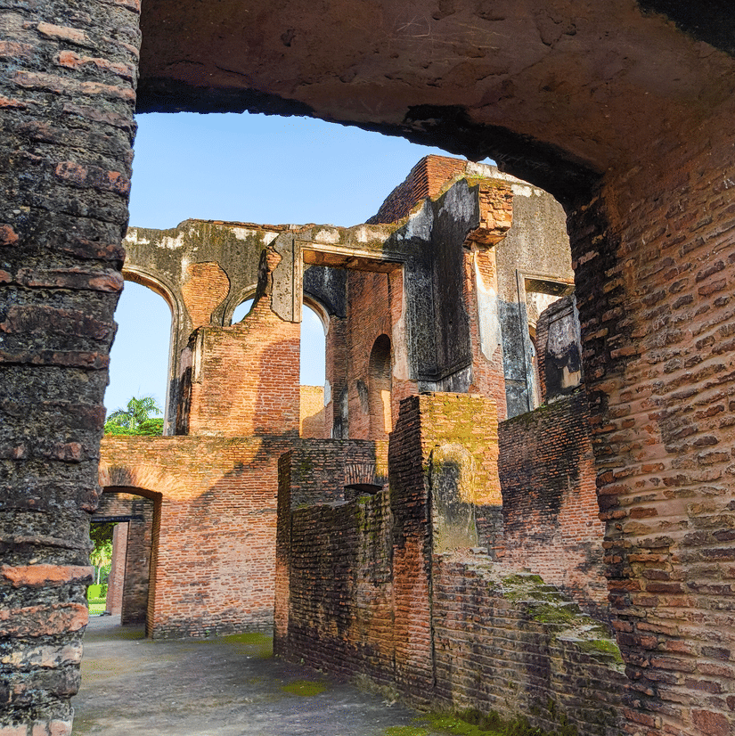 A view of the moss covered walls of The Residency, Lucknow, through one of the arched doors.  The tall walls are visible through the doorway.