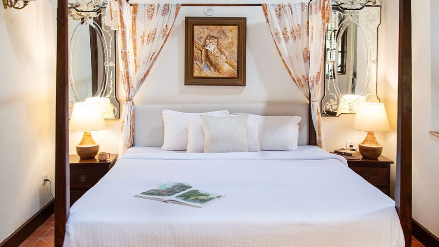 An image of a bedroom with poster beds and bedside table with lamp on either side -Lamrin Ucassaim Hotel, Goa