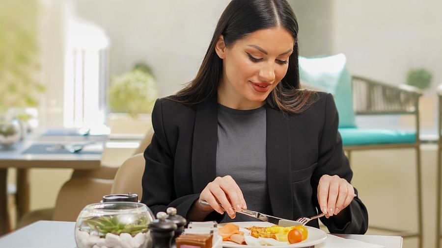 A woman enjoying her food inside La Patio - La Maison Hotel, Doha